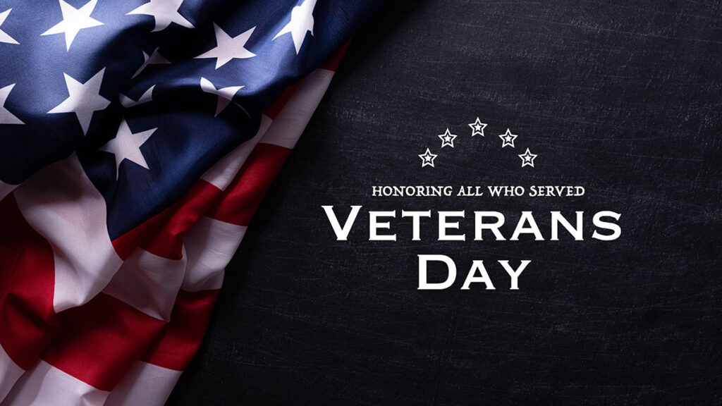 Happy Veterans Day. American flags with the text thank you veterans against a blackboard background.